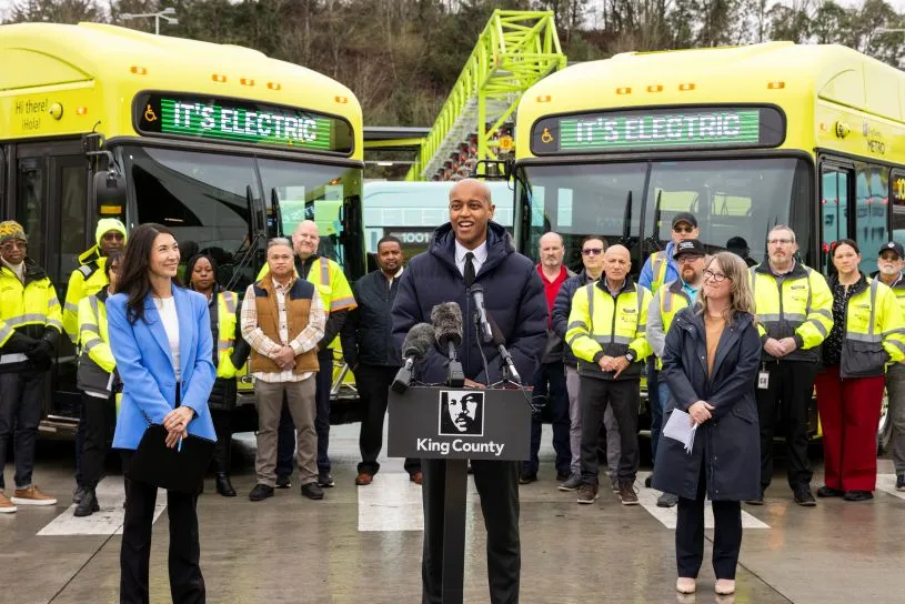 Executive Zahilay stands in front of new yellow electric buses with Councilmember Steffanie Fain and Metro General Manager Michelle Allison